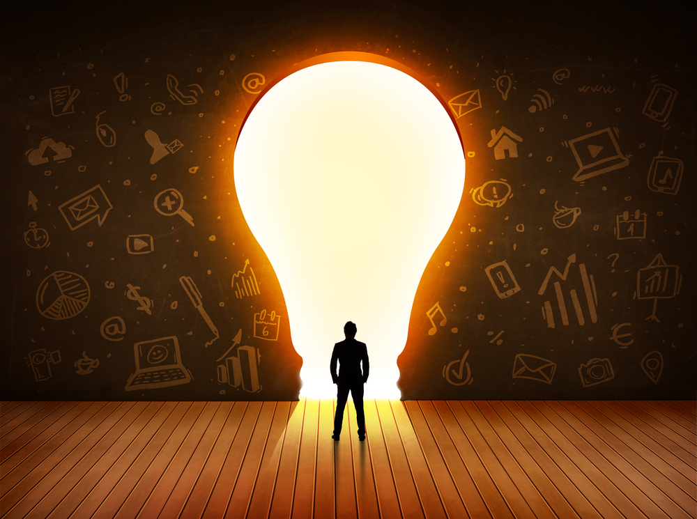 Business man looking at bright light bulb in the wall