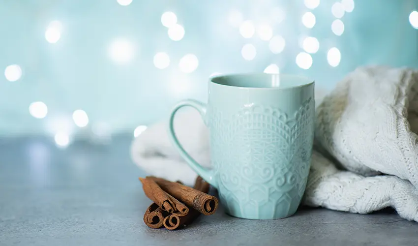 A warm setting with blue mug, towel and cinnamon sticks