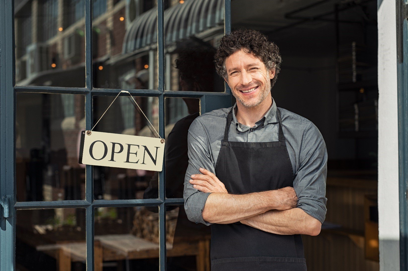 Small business owner standing next to an open sign