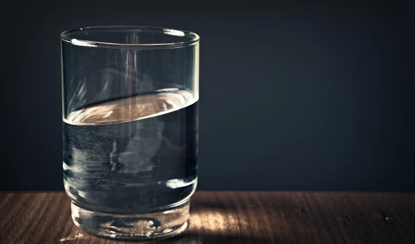 glass half full of water on a wooden surface