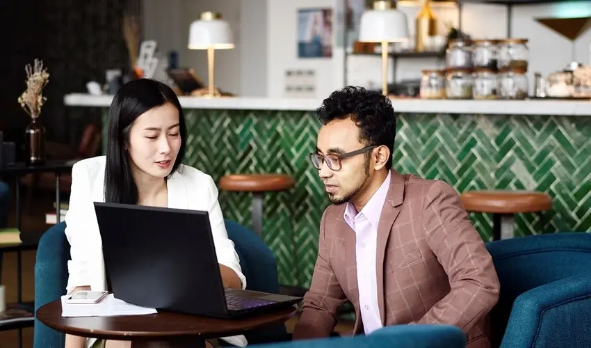 Two people looking at a computer screen in a cafe