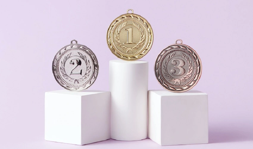 Medals on white podiums with a light purple background
