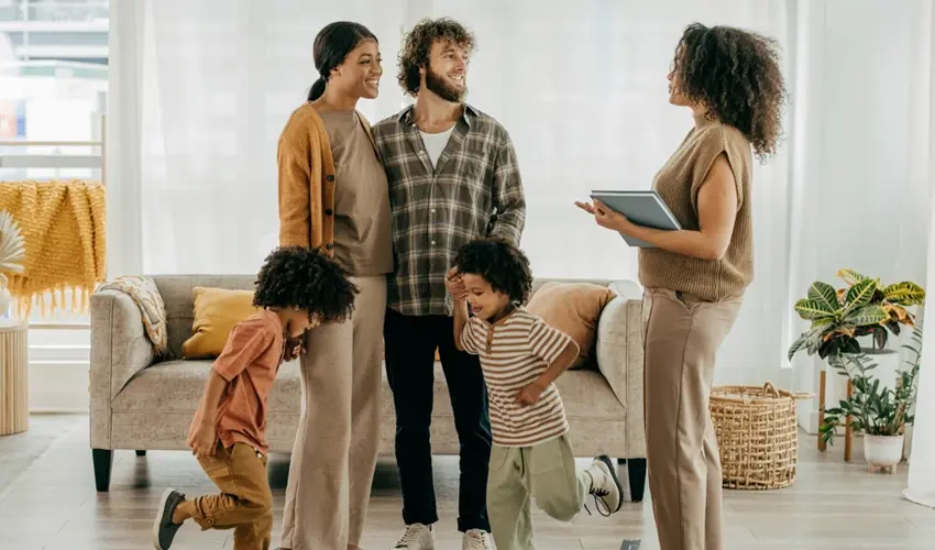 a family talking with a woman with a clipboard in a living room
