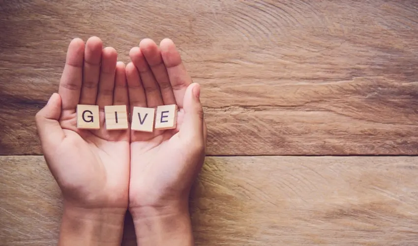 hands holding scrabble tiles spelling out 