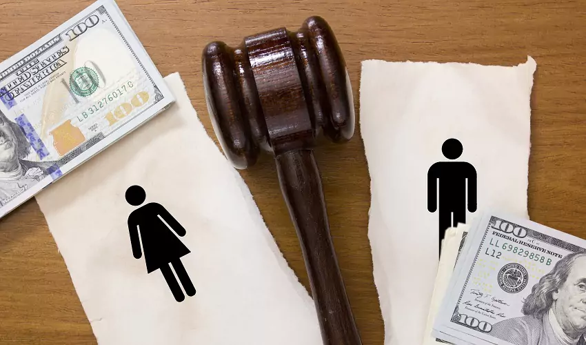 Gavel in between woman and man stick figures and money