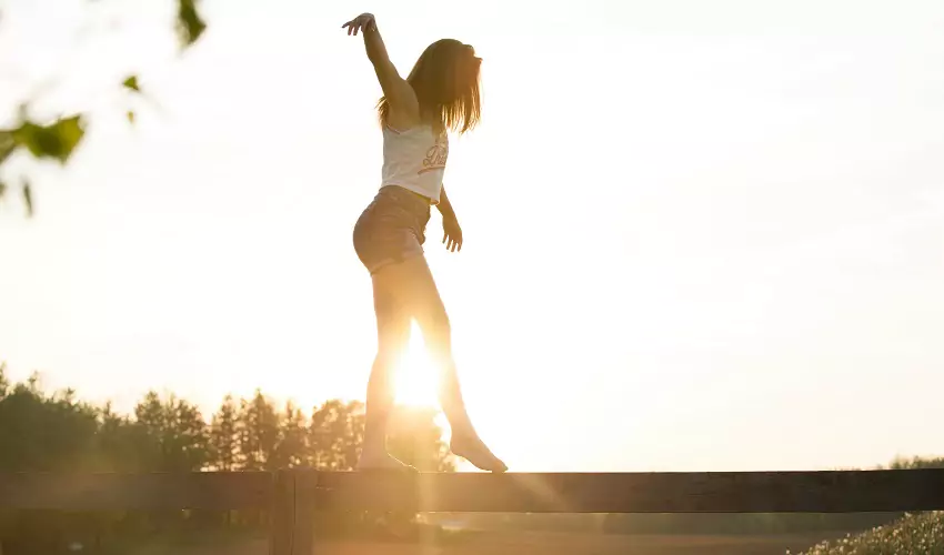 Girl balancing on a beam, backlit by the sun