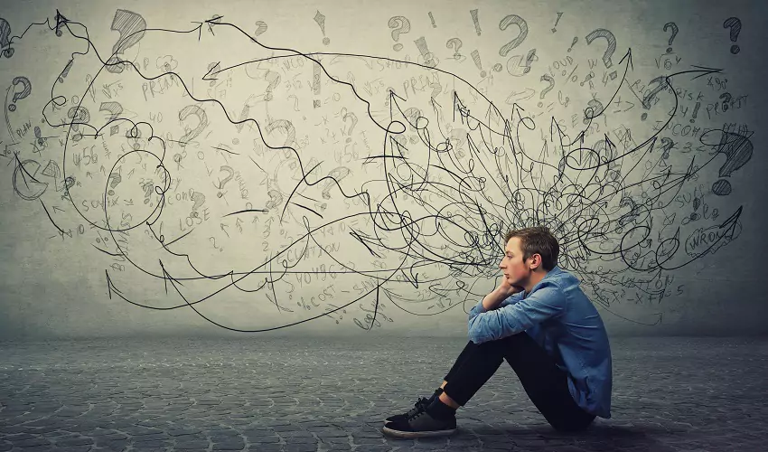 pondering man sitting on floor with chaotic lines coming out of his head