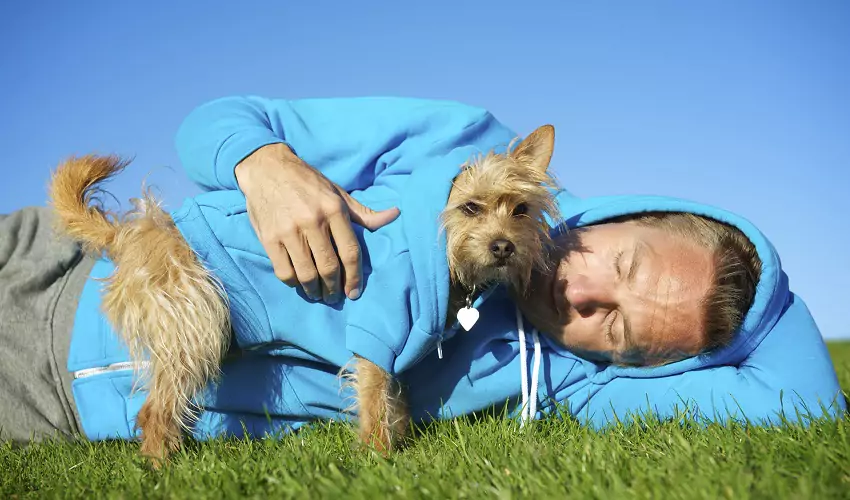 Man lying down earing a matching hoodie as dog