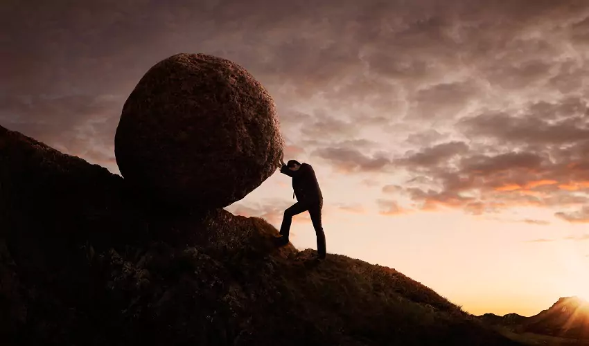 Man pushing boulder up mountain