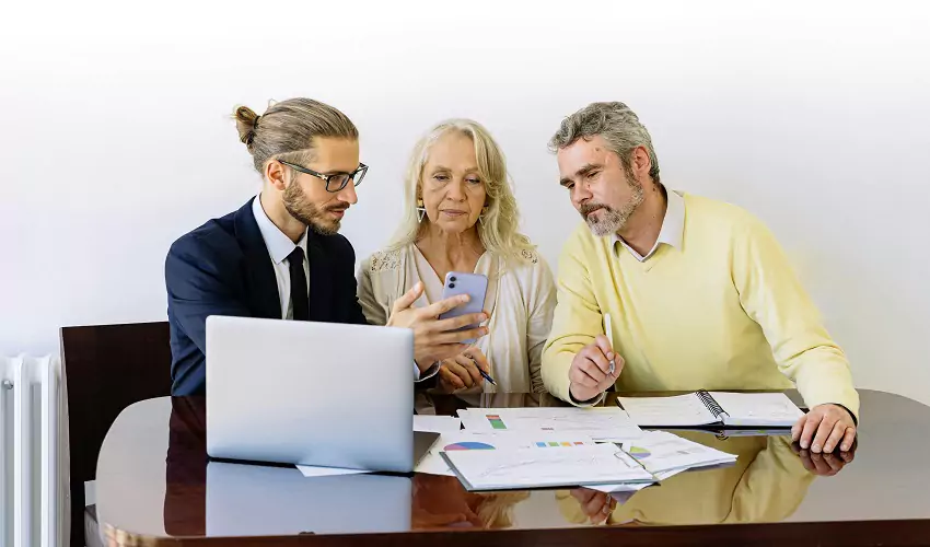 Man talking to older couple with computer and forms