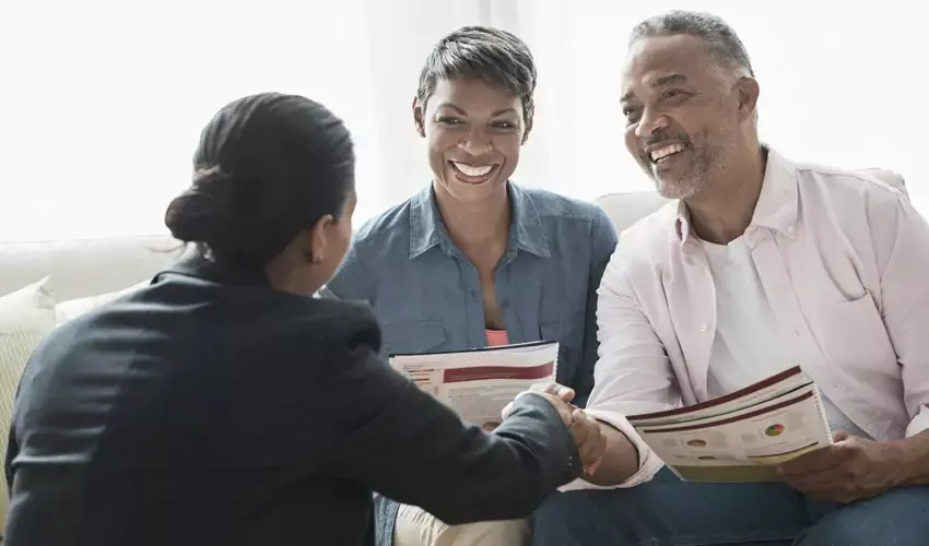 Older couple shaking hands with woman