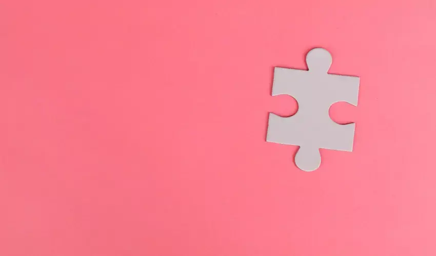 white puzzle piece on a pink background