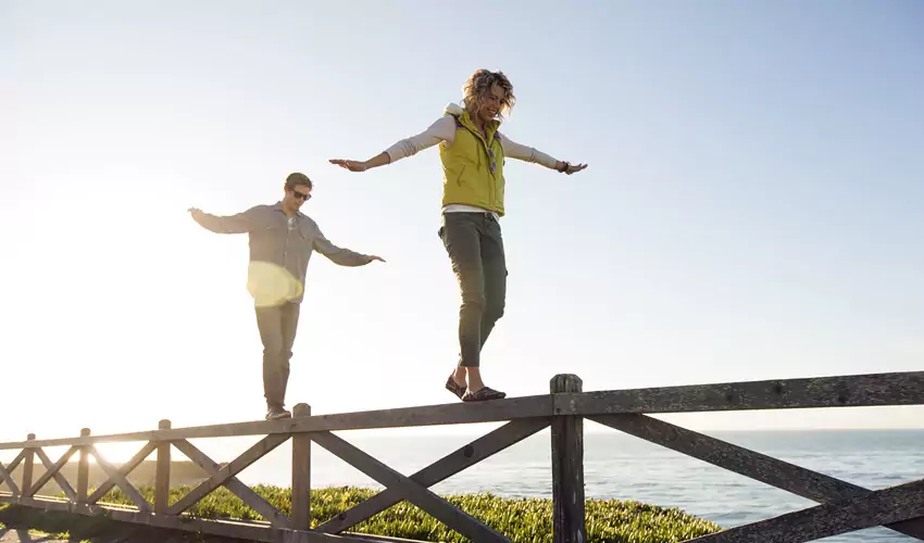 Two people balancing on fence