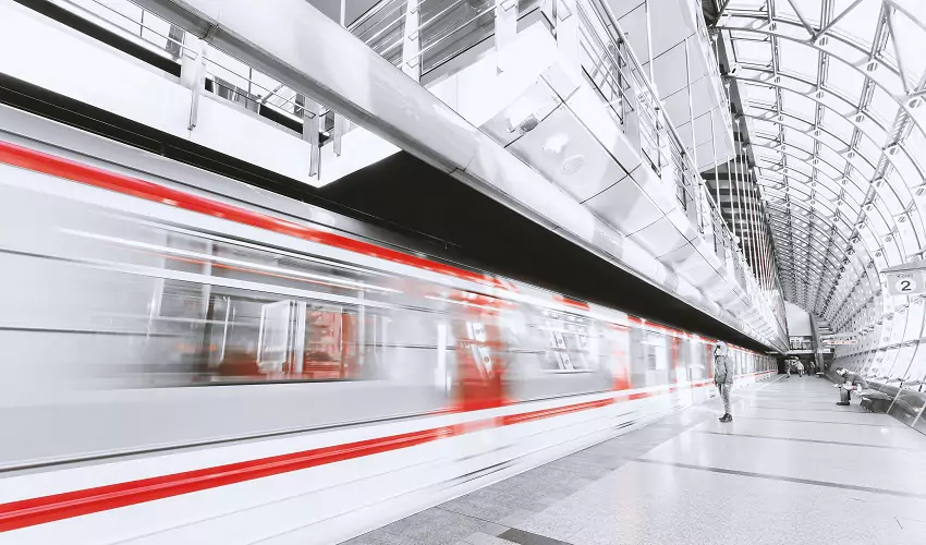 White bullet train with red stripes speeding through a station